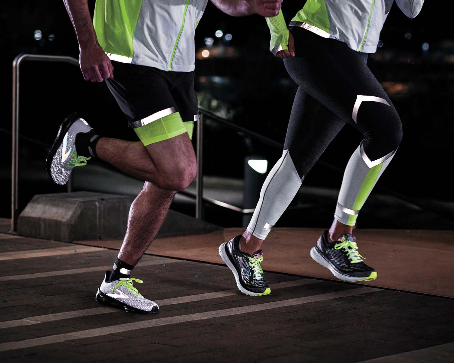 Close up of two people running in reflective shorts and reflective tights. 