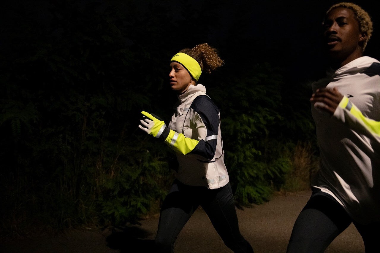 Two runners running along road in the dark