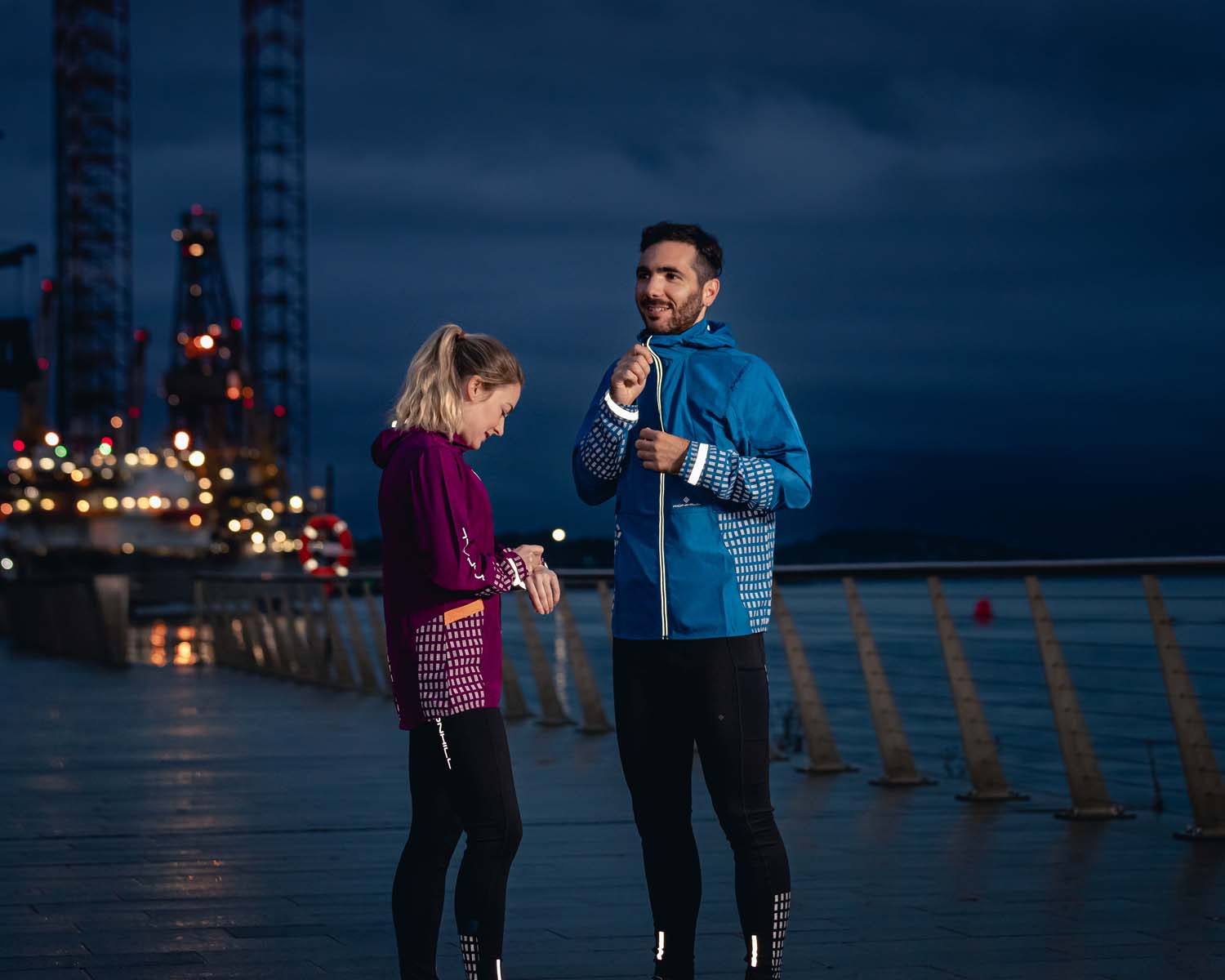 Two runners standing next to water in reflective clothing
