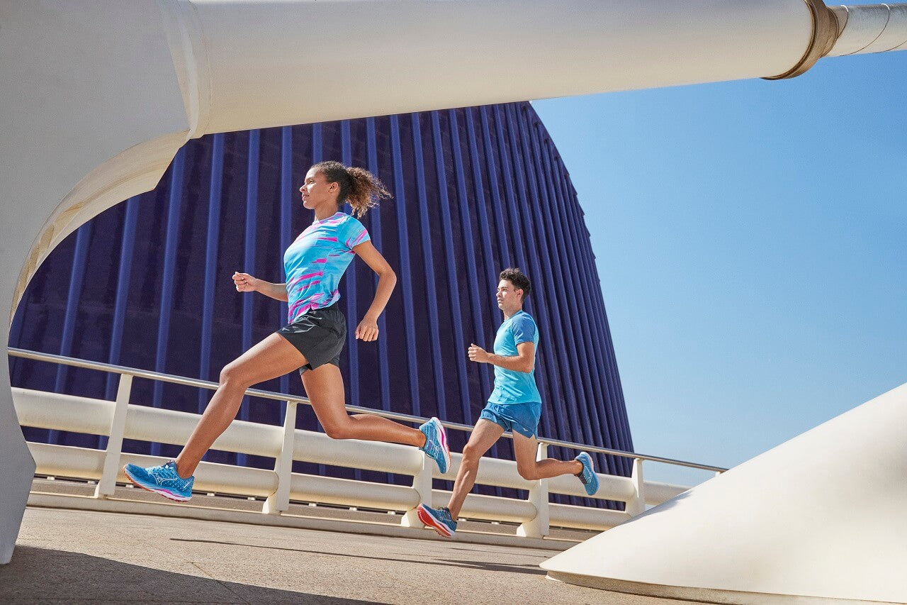 Female and male runner running on bridge in sunshine