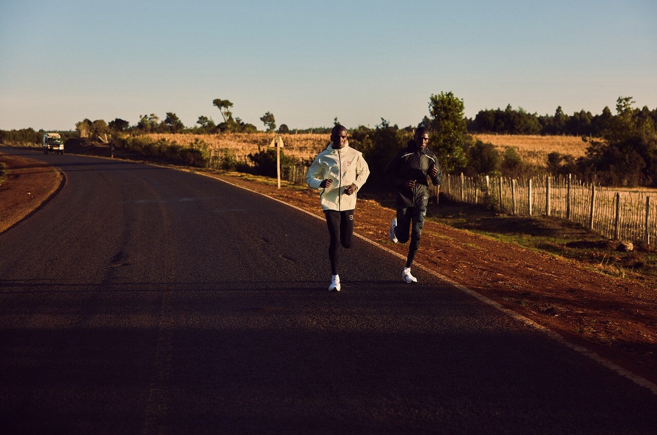Two runners running along a road at dusk