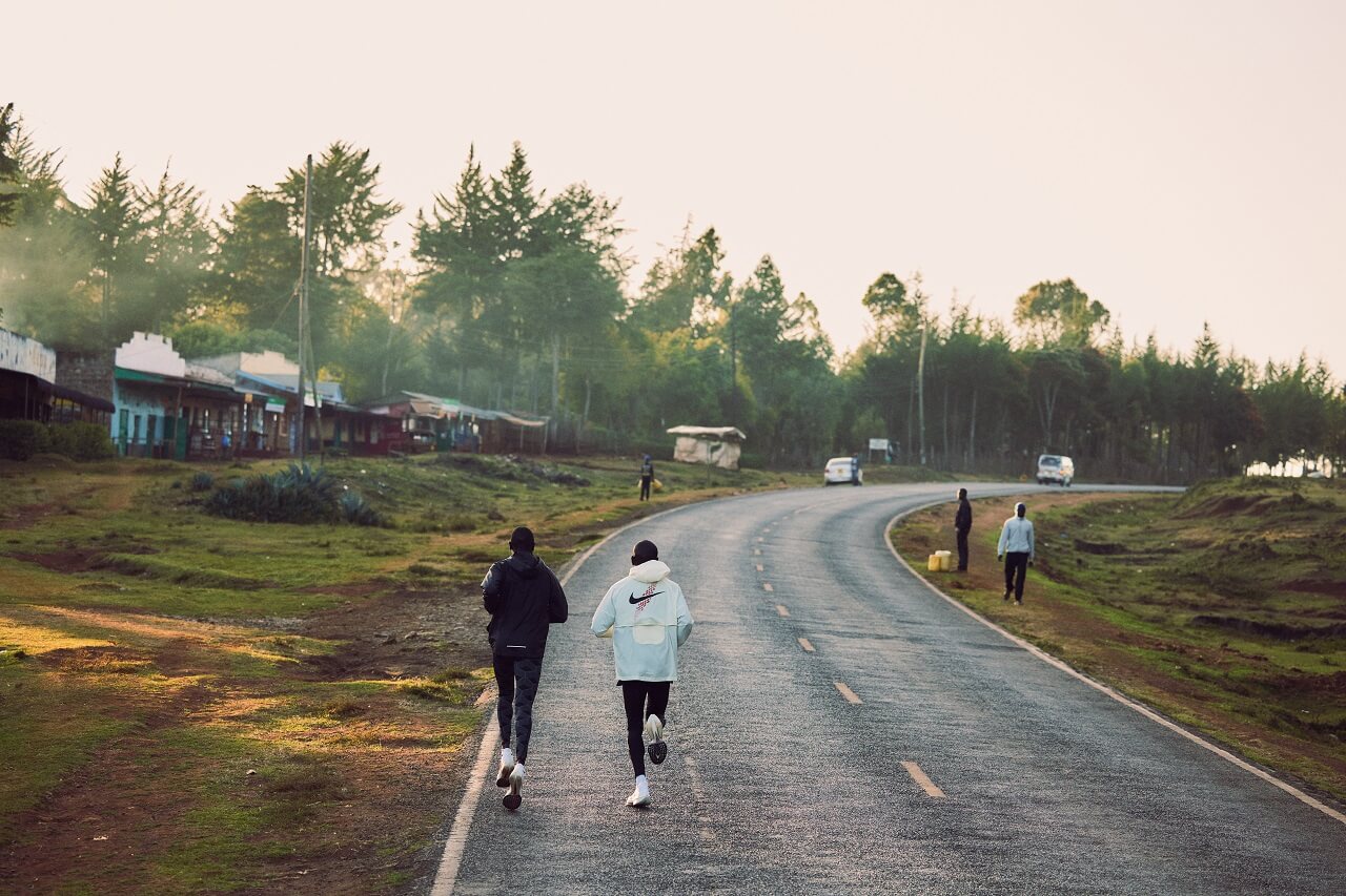 Two runners running into the distance on a road in daylight