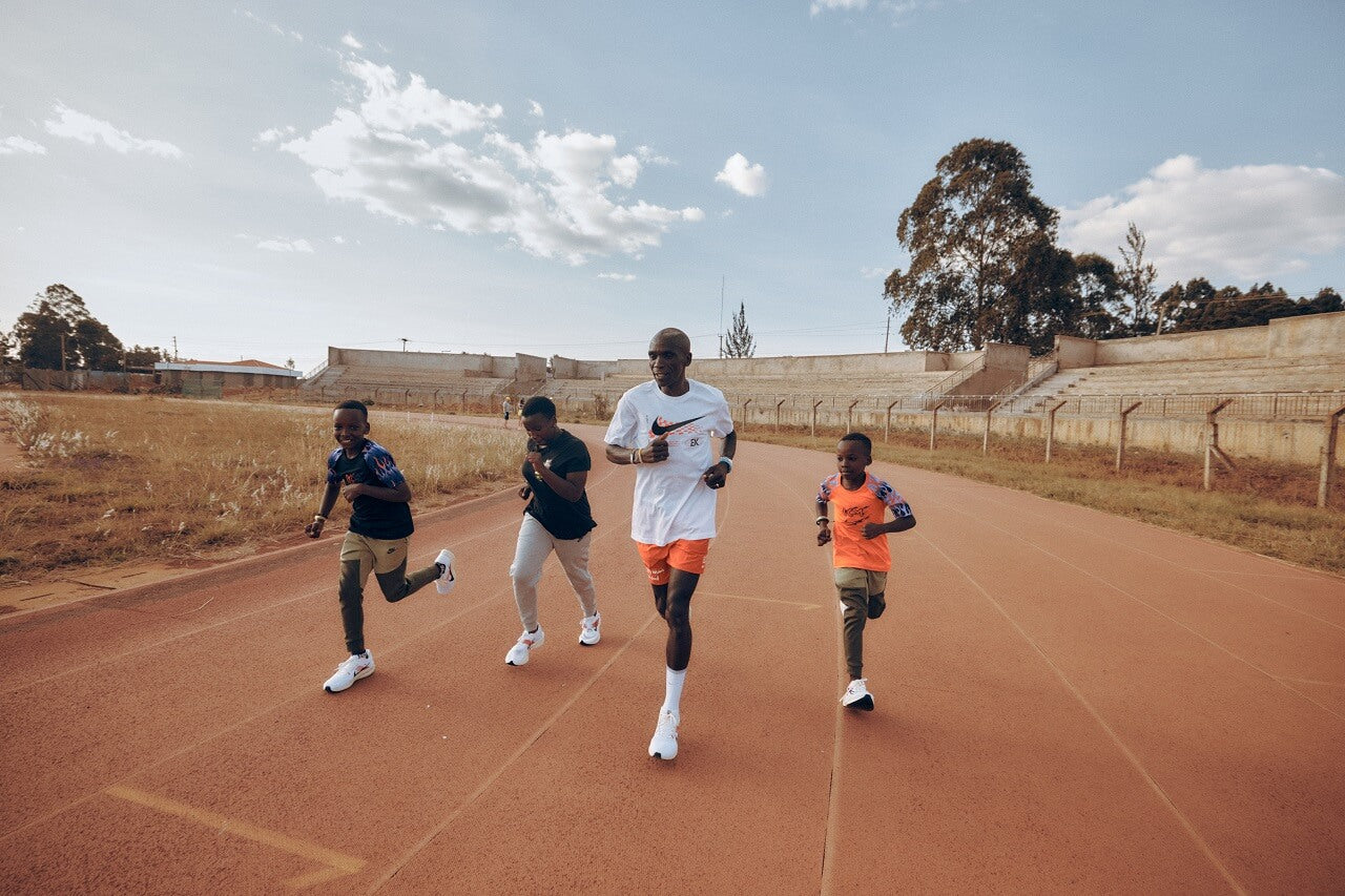 Eluid Kipchoge running alongside his wife and children on a running track