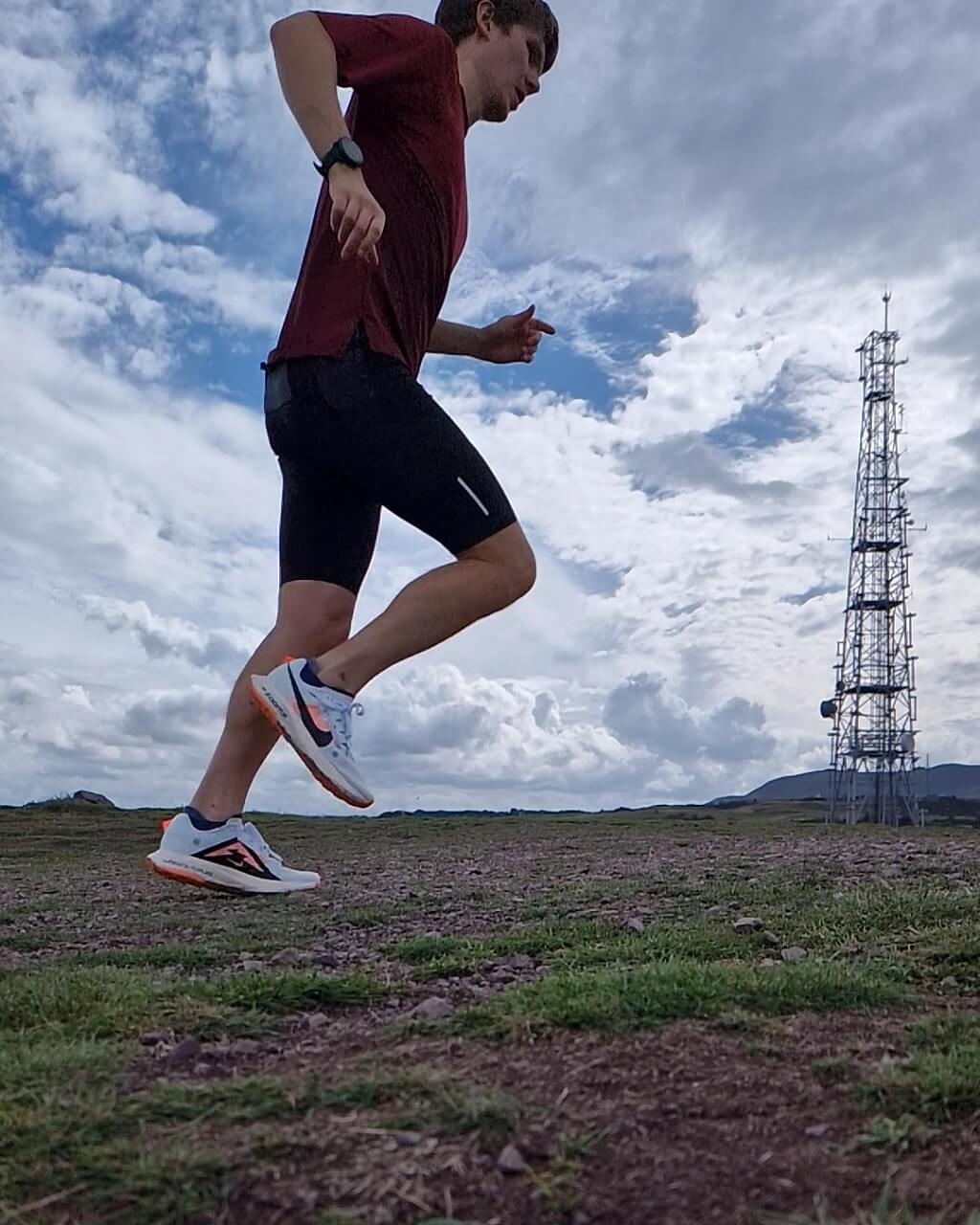 Runner running on hill summit with comms mast in the background