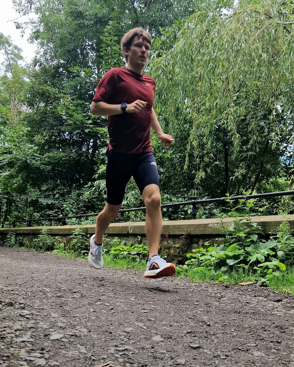 Male runner running along gravel trail in woods