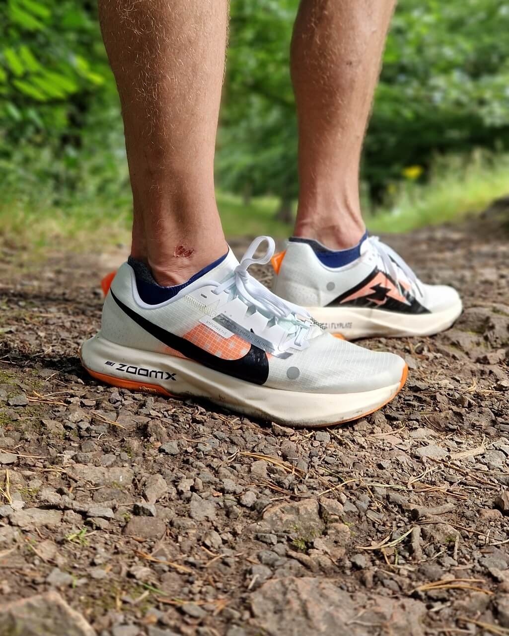 Runner standing on a gravel trail in white Nike running shoes