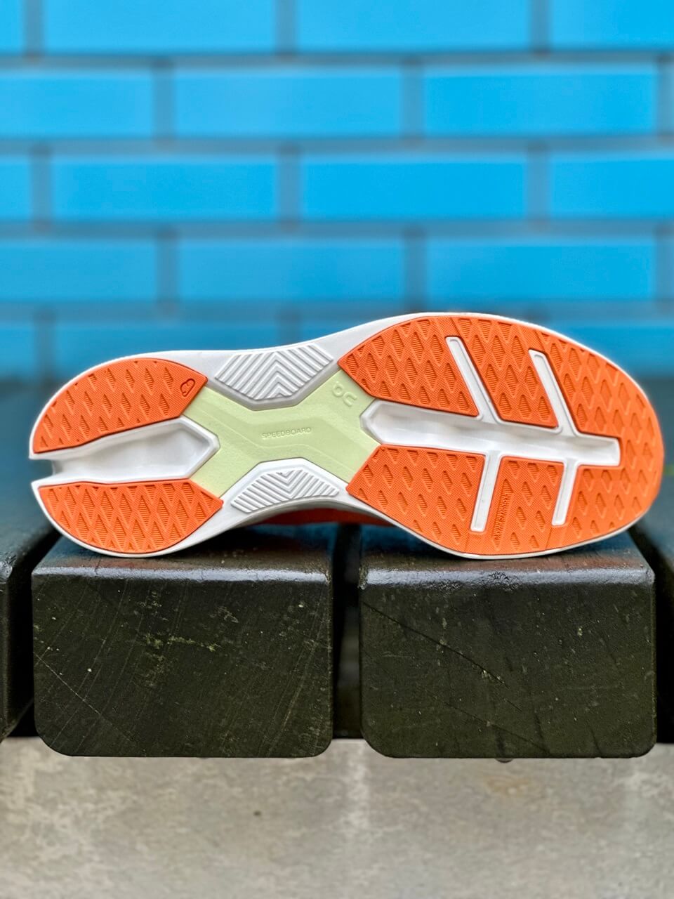 Outsole of On Cloudeclipse running shoe against blue tiled wall backdrop.