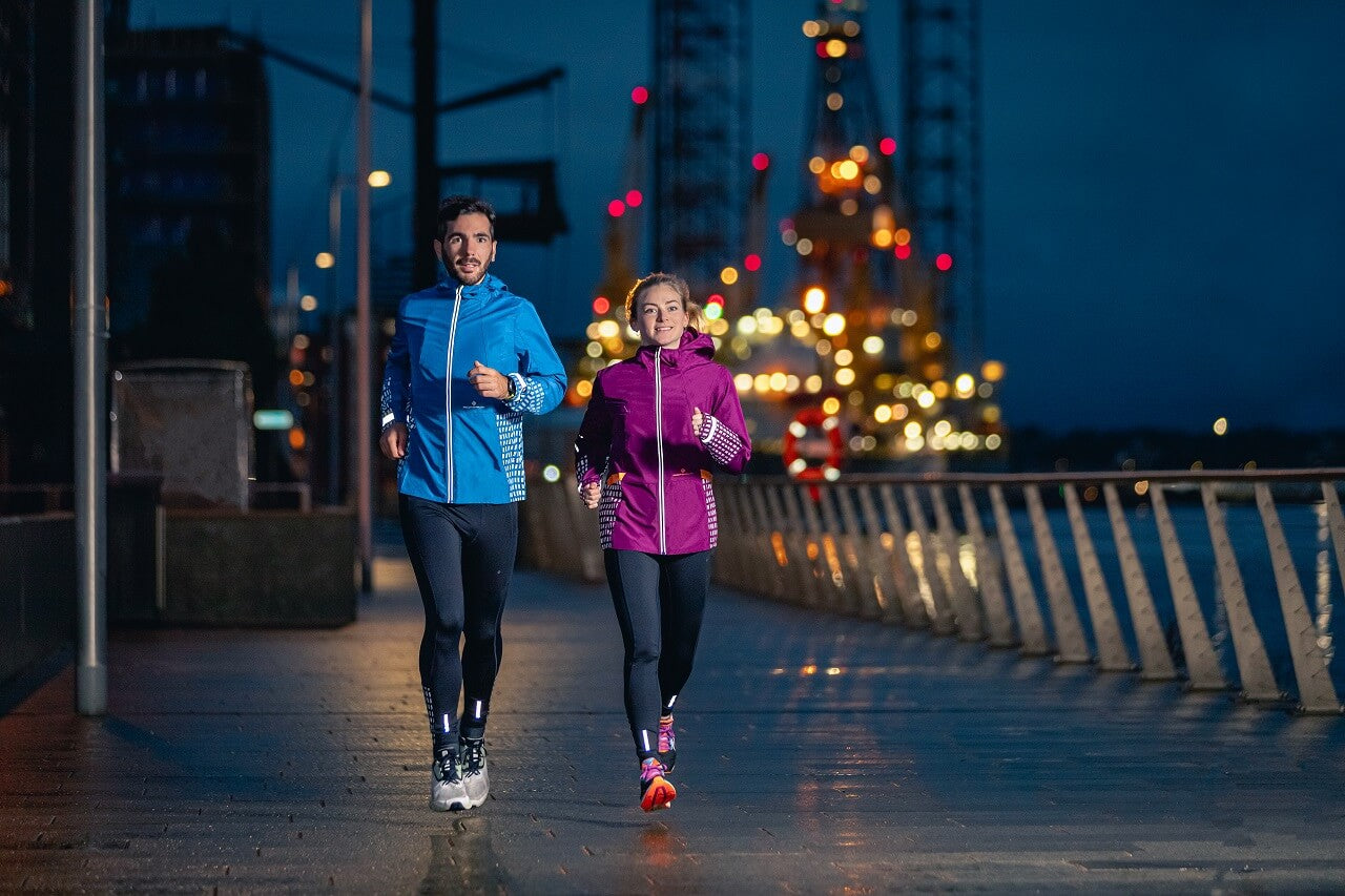 Two runners running along waterfront at night