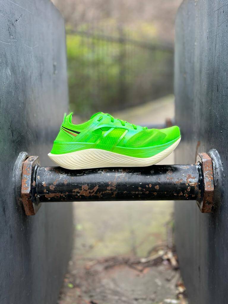 Left medial view of Saucony Endorphin Elite road racing shoe in slime green balanced on industrial pole