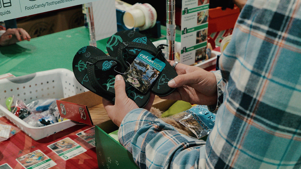 Cobian Volunteer Putting Sandals Into a Shoe Box