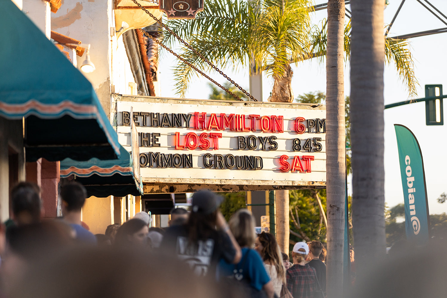 Close up shot framed between a crowd showing the La Paloma Theatre billboard reading, "Bethany Hamilton 6pm."