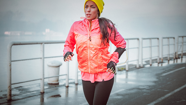 10 Dicas para atividade física no inverno - mulher de laranja correndo no frio e na chuva