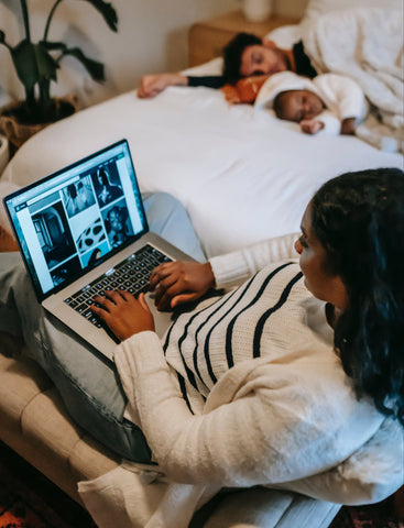 Woman working on her computer while her husband and child is asleep, Hybrid work life