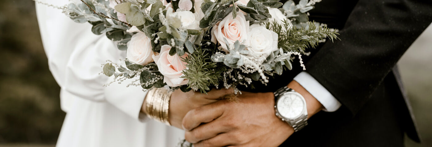 Cette image montre un couple de marié avec un bouquet de fleurs dans les mains