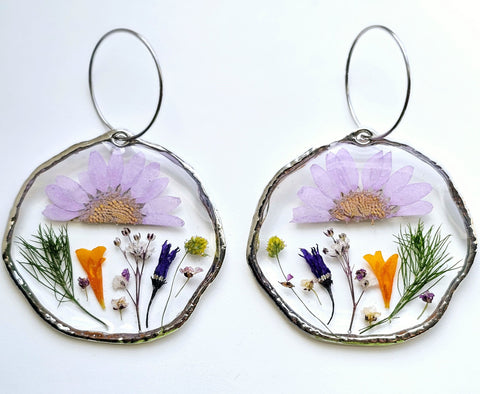 1 pair of resin earrings on a white background. It's a combination of fresh herbs from garden and an assortment of pressed and dried flowers