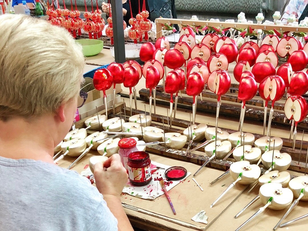 Hand decorating a glass apple Christmas decoration