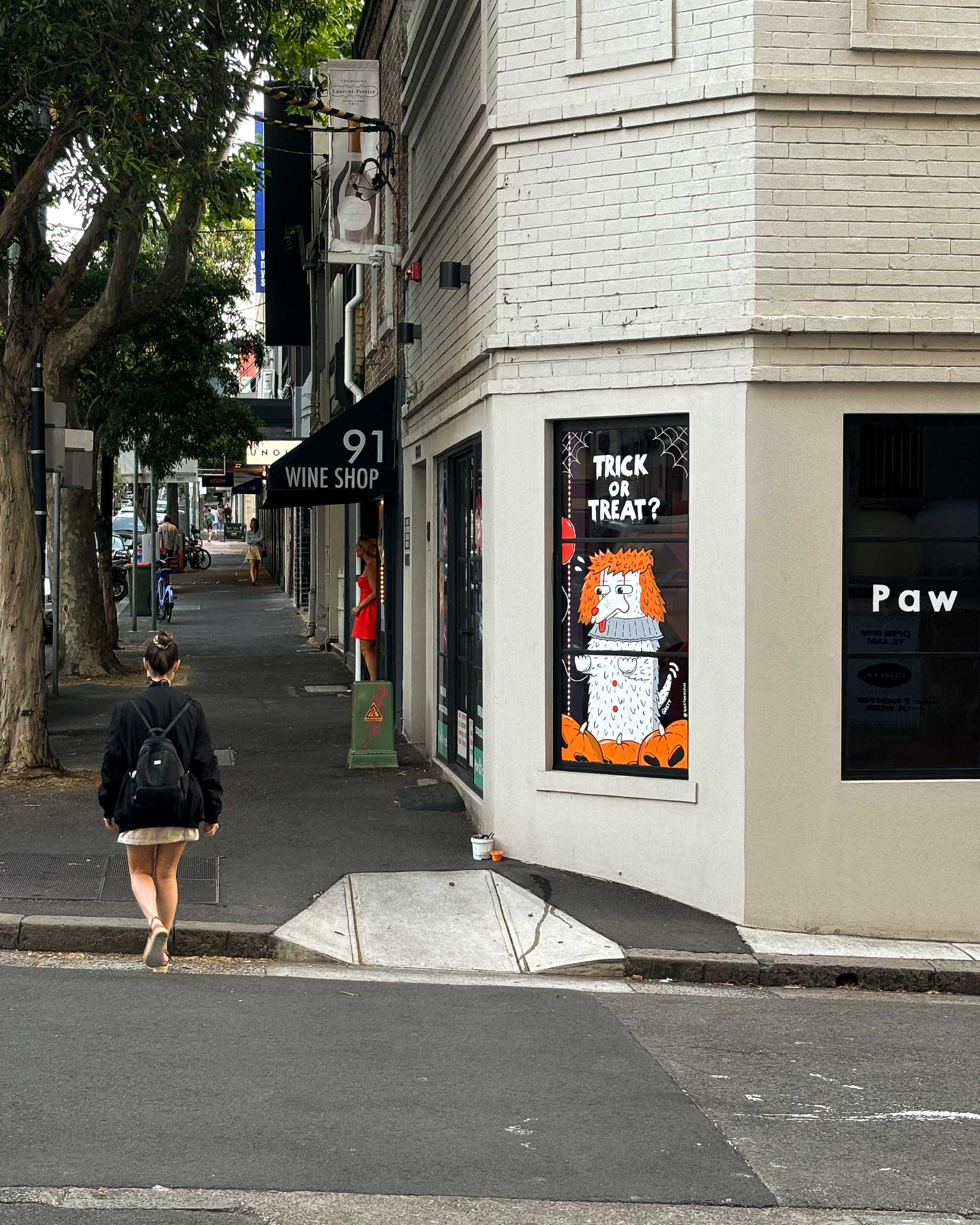 Artistic window painting at a pet shop in Darlinghurst, Sydney, showcasing adorable dogs and festive Halloween decorations.