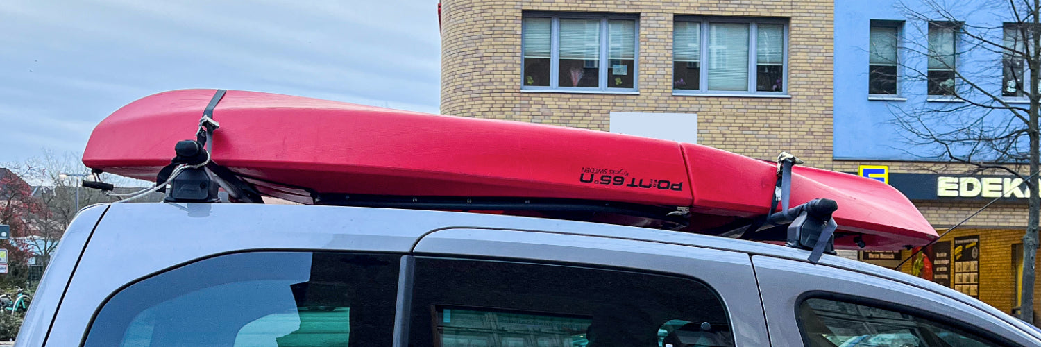 Kanu auf einem Autodach befestigt mit Spanngurten