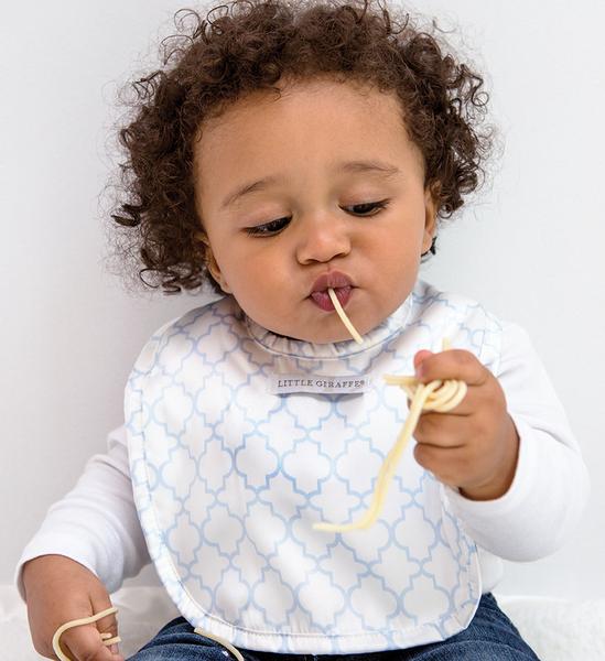 Baby eating spaghetti wearing a cloth baby bib