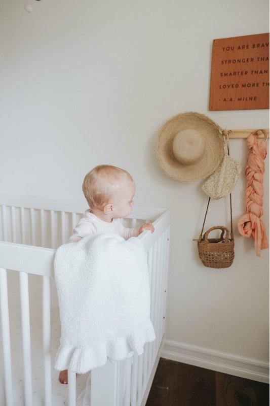 Baby in crib with white baby blanket