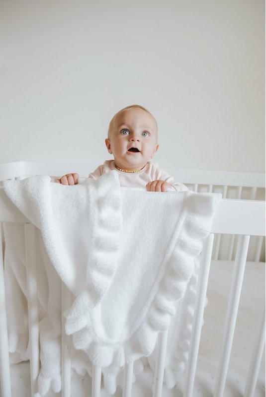 Baby in crib with white baby blanket