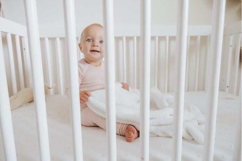 Baby in crib with white baby blanket