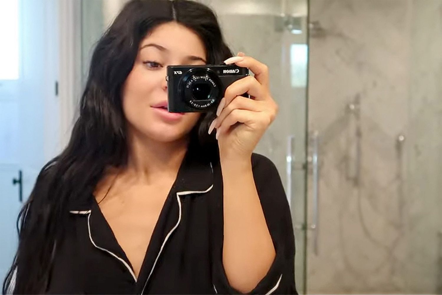 Woman taking a selfie with a camera in a mirror.