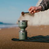 Preparing a cup of coffee on a beach with the Stanley filter