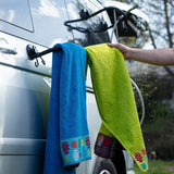 Towels drying on a suction cup rack attached to the body of a van