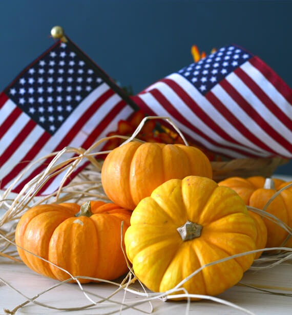 two American flags among pumpkins