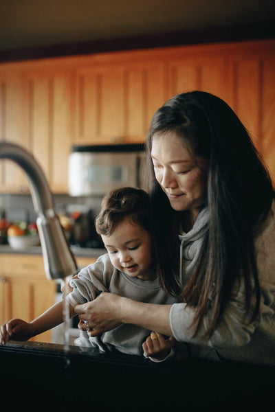 kid washing hands with mom