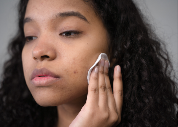 femme métisse qui applique un produits cosmétique sur le visage