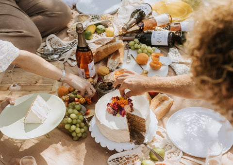 Friends at a picnic, drinking award-winning, alcohol-free wine and cake and fruit and cheese. 