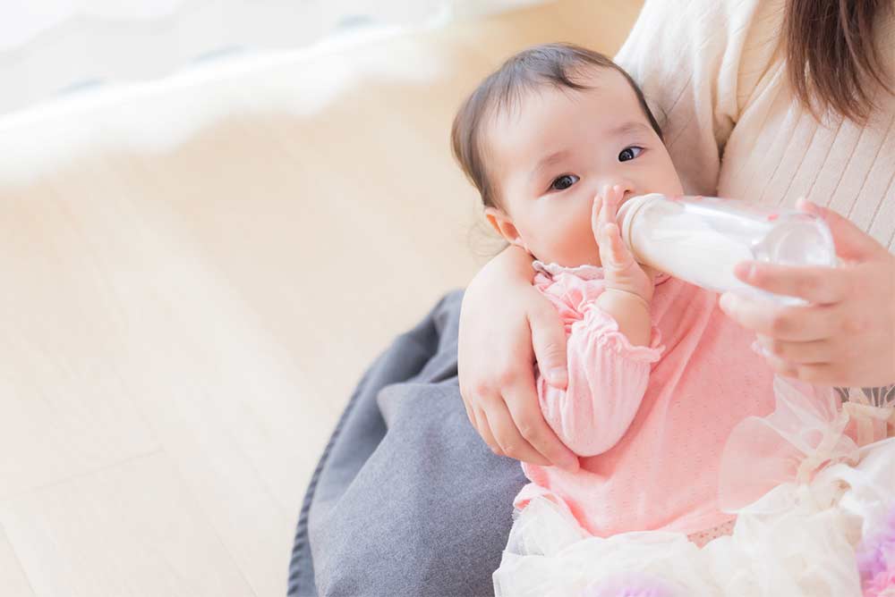 ママに抱かれてミルクを飲む赤ちゃん