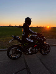 woman with motorcycle in front of sunset