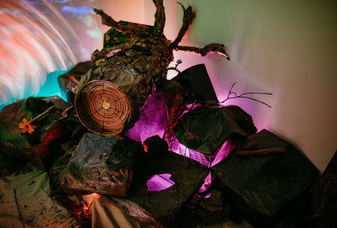 a forst scene crafted from recycled materials made into a log with a kaliedscope on top of rocks lit from below