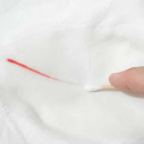Removing pen ink stains with a cotton bud.