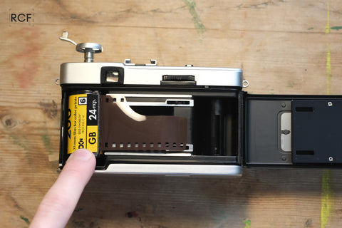 [Image 3: Film cartridge being inserted into the camera]