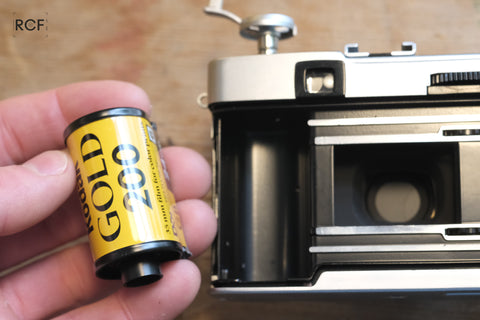 [Image 13: Film cartridge being removed from the camera]