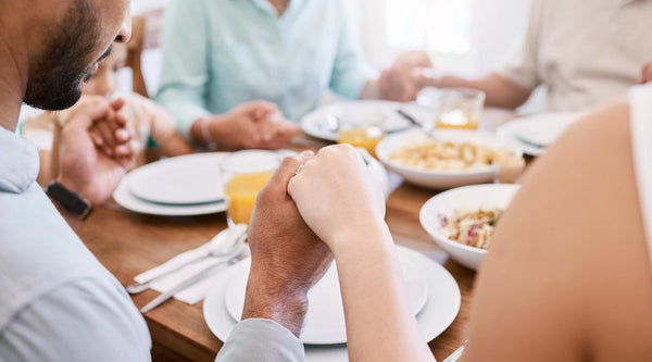 Power of house blessings, a family holding hands around a dining table.