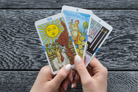 Tarot card reading, person holding three tarot cards.
