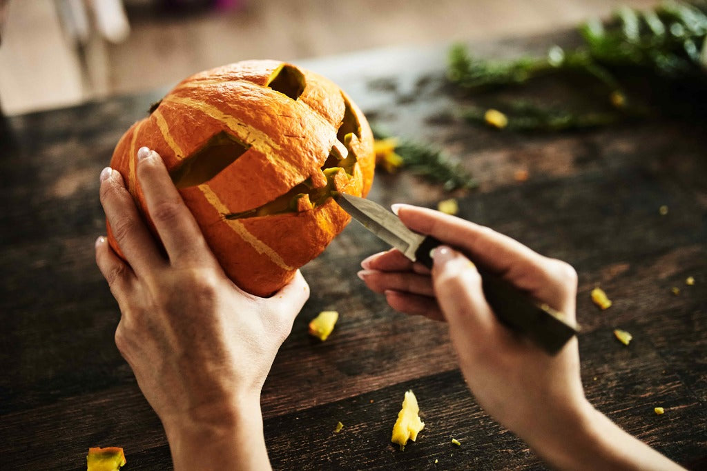 Halloween for adults, hands carving a pumpkin.