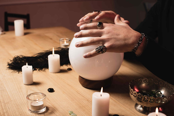 Therapeutic benefits of psychic readings, person placing hands on a crystal ball near candles.