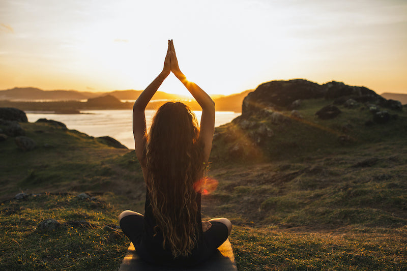 Spiritual self-care, woman meditating outdoors.