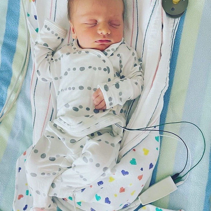 A newborn baby lying on a hospital bed.