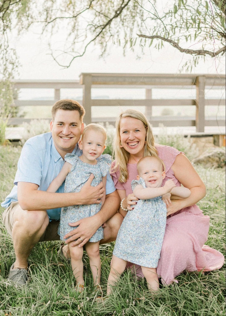 Photo of Emily’s family in front of bridge on grassy lawn.