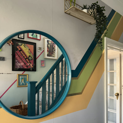 green and yellow striped angular painted design on hallway wall with circular mirror