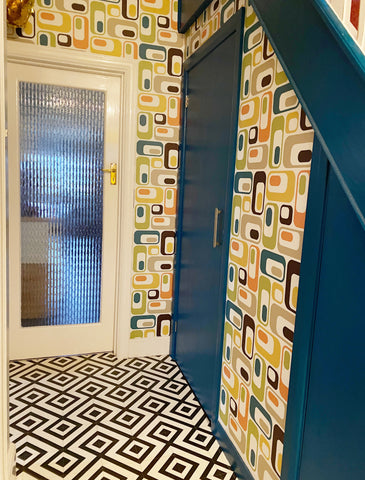 Colourful hallway with black and white tiled flooring and a retro multicoloured patterned wallpaper