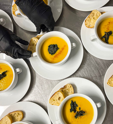 Roasted Butternut Squash Soup in white bowls with chef hands in black gloves