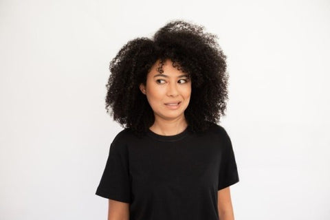 alt="Light skinned african american girl with curly bushy hair and black t-shirt looking to the side confused."